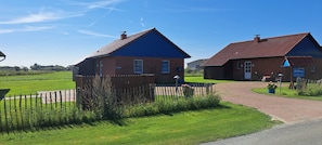 A rural setting with two brick buildings, a wooden fence, and a paved path.