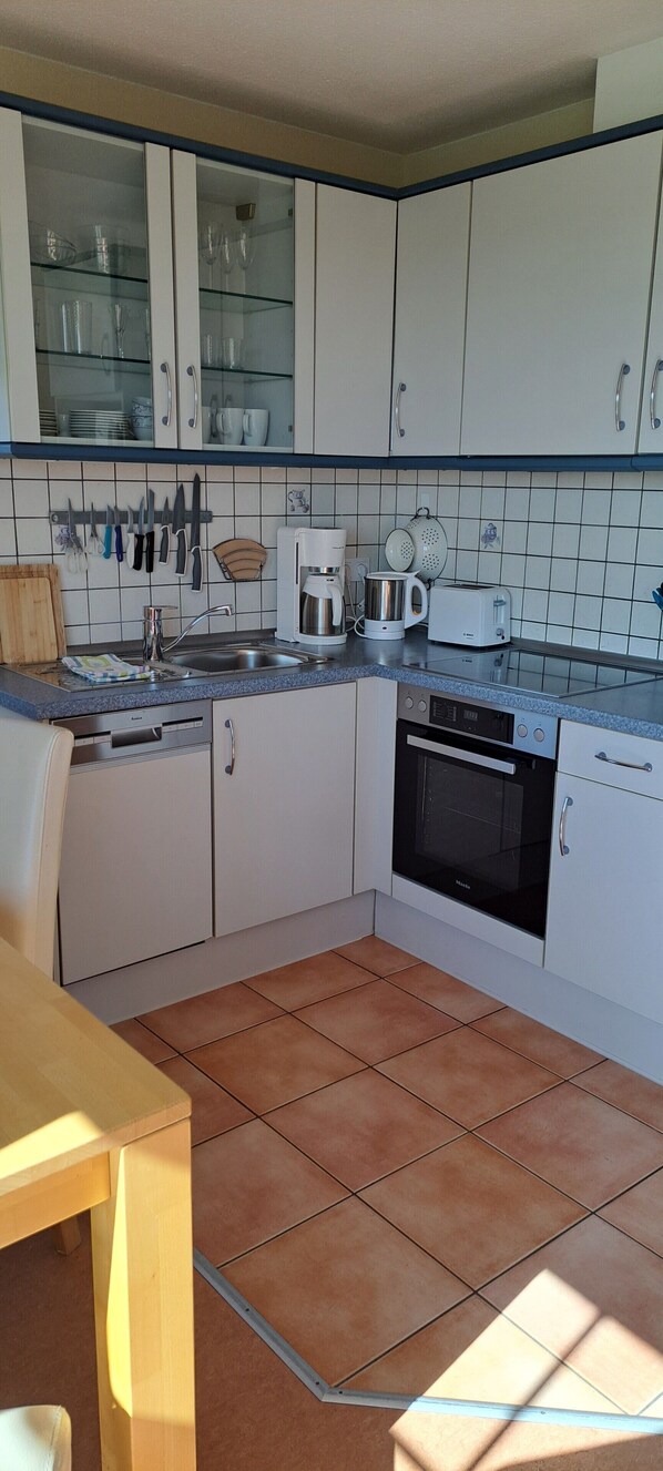 A kitchen with white cabinets, a sink, a coffee maker, a toaster, and a stove.