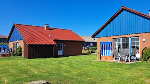 A residential property with a red-tiled roof, a brick building, a blue awning, and a satellite dish. - Holiday Home 'Ferienhaus Heverstrom' with Shared Garden and Wi-Fi (Pellworm)