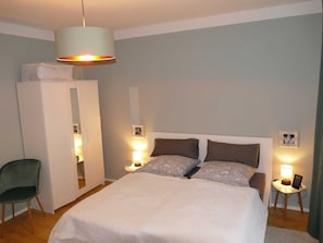 A bedroom with a bed, bedside tables, a wardrobe, and a hanging light fixture.