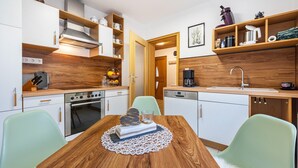 Eine moderne Küche mit weißen Schränken, Holz Arbeitsplatten, einem Esstisch mit Stühlen und einer Kaffeemaschine.