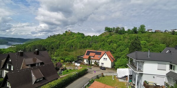 Un quartier résidentiel avec des maisons, une colline surmontée d’une structure en forme de dôme, et une étendue d’eau visible au loin.