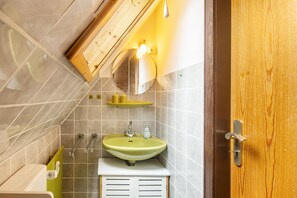 Une salle de bain avec un lavabo vert, un miroir, un porte-serviettes et une porte en bois.