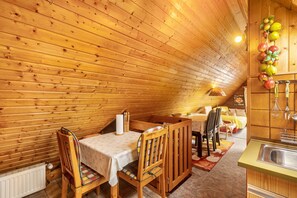 A cozy wooden interior with a dining area, a kitchen with a sink, and a hanging fruit decoration. - Apartment 'Wohnung Kranich Mit 1 Schlafzimmer' with Lake View and Wi-Fi (Waldeck)