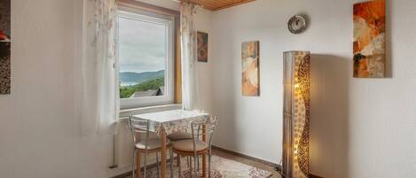 Ein Essbereich mit Tisch und Stühlen, einem Fenster mit Vorhängen und Wandbildern.