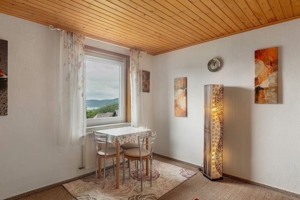 Un coin repas avec une table et des chaises, une fenêtre avec des rideaux et des œuvres d’art murales.