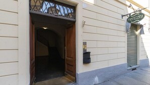 An open wooden door leading into a building with a metal gate above it and a sign above the door that reads 'Pasticceria'. - GuestHost - San Donato & Piazza Statuto Appt x3 with Balcony (Torino)