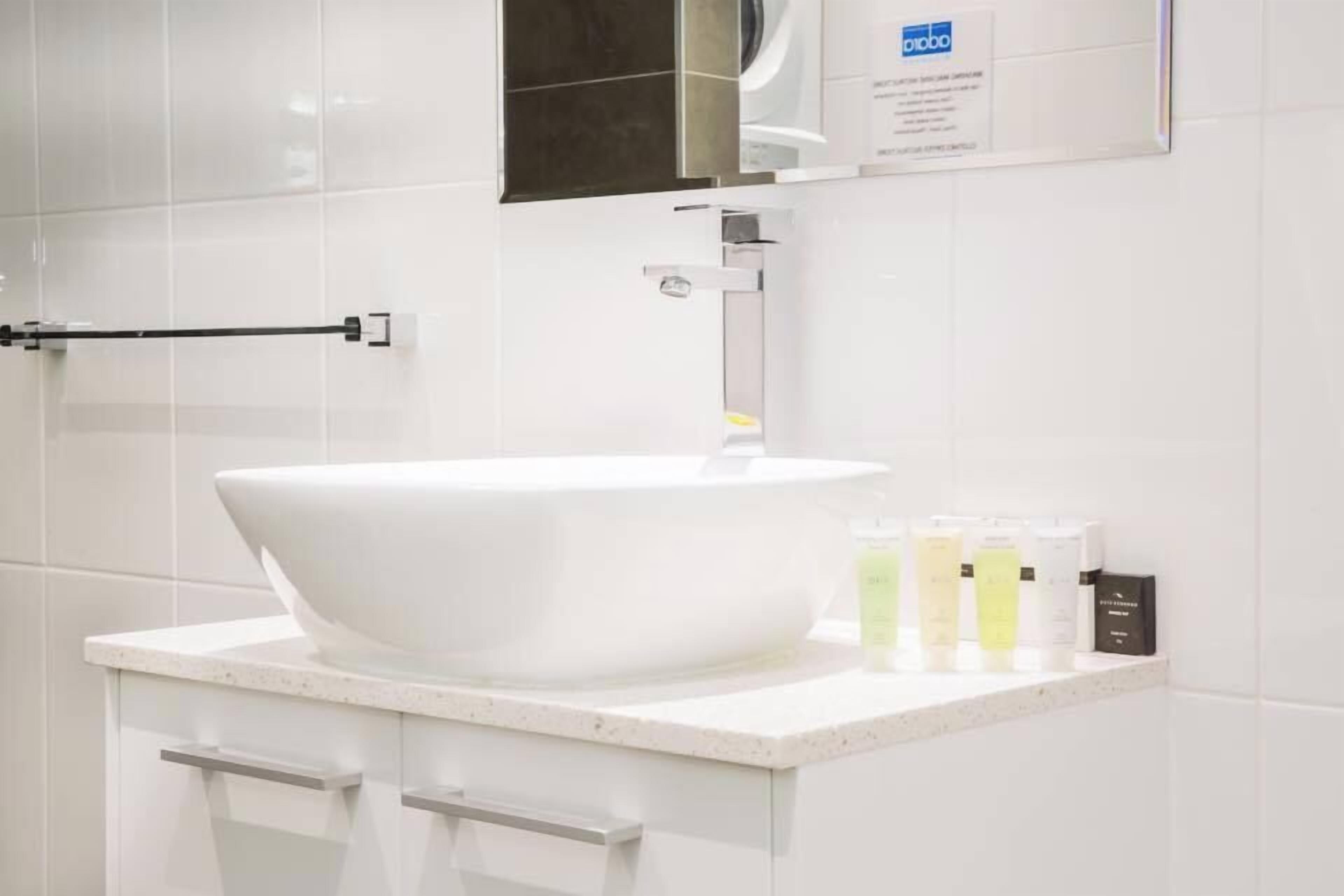 A modern bathroom with a large white sink, a towel rack, and a mirror.