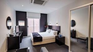 Een moderne hotelkamer met een groot bed, een bureau, een stoel, een spiegel en een kledingkast.