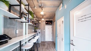 Une cuisine moderne avec des tabourets de bar, un comptoir sur lequel se trouve un ordinateur portable, et une porte indiquant « Salle de douche ».