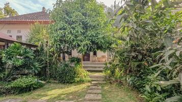 Un sendero de jardín que conduce a una casa con techo de tejas y un porche con sillas.