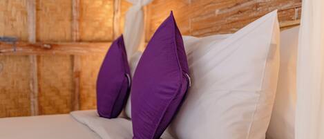 A bed with white and purple pillows, a wooden headboard, and a white canopy.