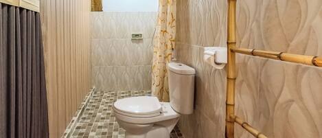 A small bathroom with a toilet, a shower area, and a bamboo shower curtain.