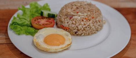 A plate with fried rice, a fried egg, and a slice of tomato on a white plate.