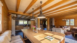 A spacious living area with a wooden dining table, sofas, and a fireplace.