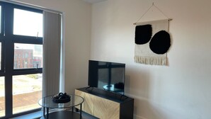 A modern living room with a large TV, a glass coffee table, and a view of the outside. - 2 Bed with Wi‑Fi, Near Central Birmingham (Birmingham)