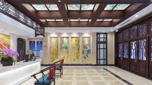 A reception area with a check-in counter, seating, and decorative panels. - Yitingzhenshe Hotel Beijing Tiananmen (Beijing)