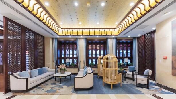 A spacious lobby with a modern design, featuring a central seating area with sofas and a round table, surrounded by decorative windows and a patterned floor. - Yitingzhenshe Hotel Beijing Tiananmen (Beijing)