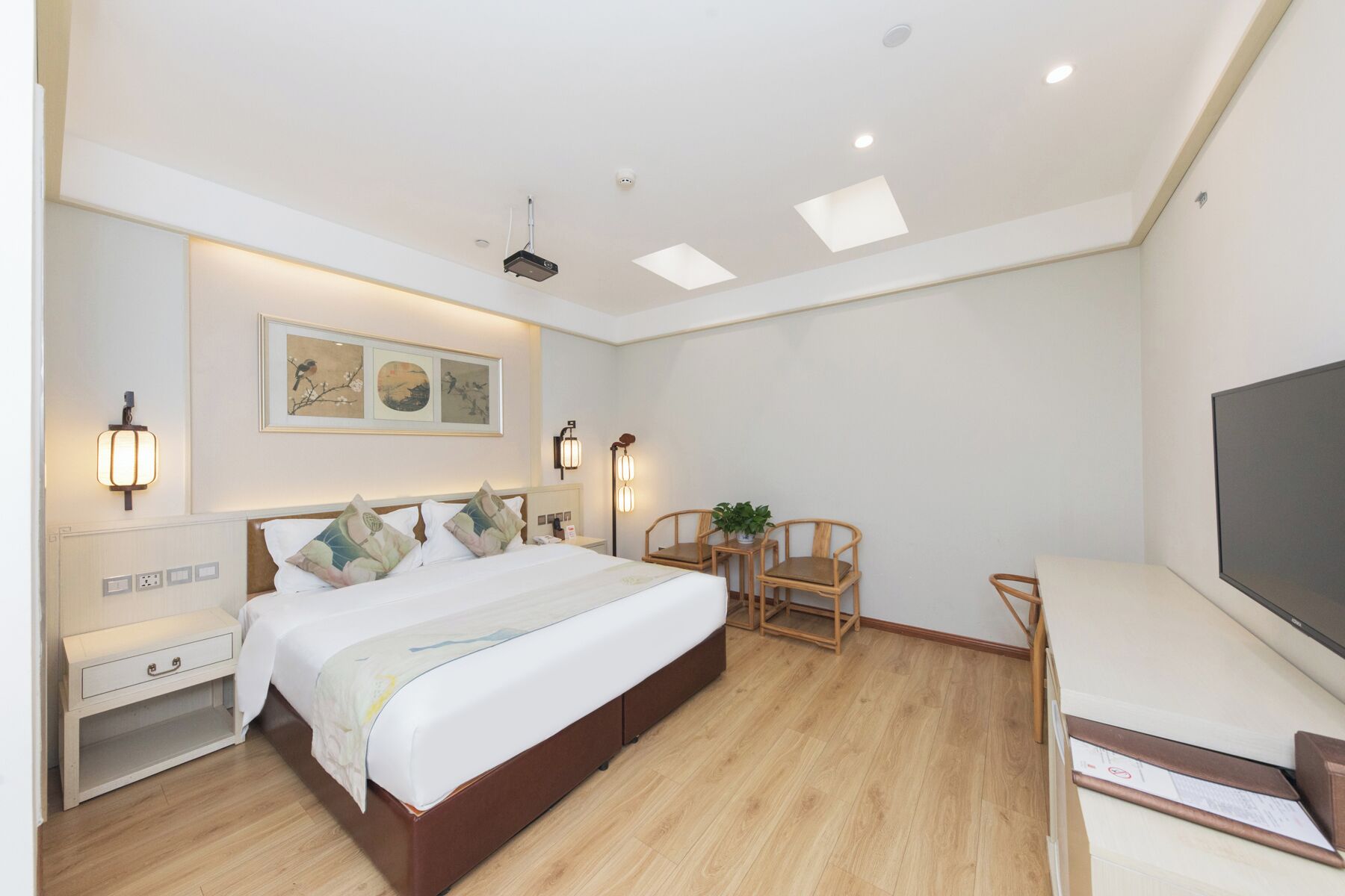 A modern bedroom with a large bed, bedside tables, a desk, and a TV.