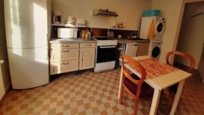 A compact kitchen with a refrigerator, microwave, stove, and washing machine.