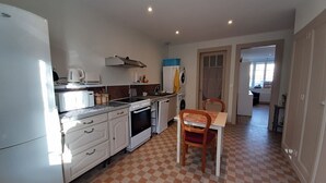 A compact kitchen with white appliances, a checkered floor, and a dining area with a table and chairs.