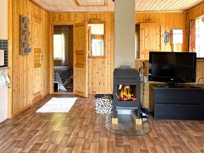 A cozy cabin interior with a central wood-burning stove, a television, and a bed with a star-patterned blanket. - 4 Person Holiday Home in Bengtsfors (Bengtsfors)