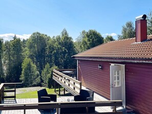 A red building with a wooden deck, outdoor seating, and a chimney.