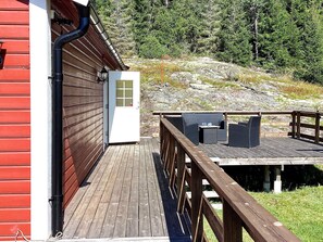 A wooden deck with outdoor furniture, a red building, and a white door with a window. - 4 Person Holiday Home in Bengtsfors (Bengtsfors)