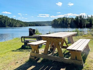 A picnic table set by a lake with a forest backdrop.