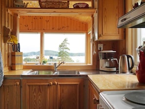 A wooden cabin kitchen with a large window, wooden cabinets, and basic kitchen appliances. - 5 Person Holiday Home in Munkedal (Munkedal)