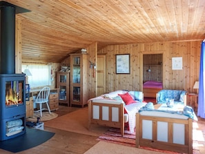 A cozy cabin with a wood-burning stove, two wooden beds, a chair, and a cabinet. - 5 Person Holiday Home in Munkedal (Munkedal)