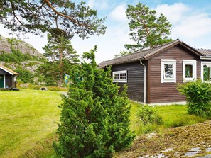 A cabin with a sloped roof, surrounded by greenery and a mountain backdrop. - 5 Person Holiday Home in Munkedal (Munkedal)