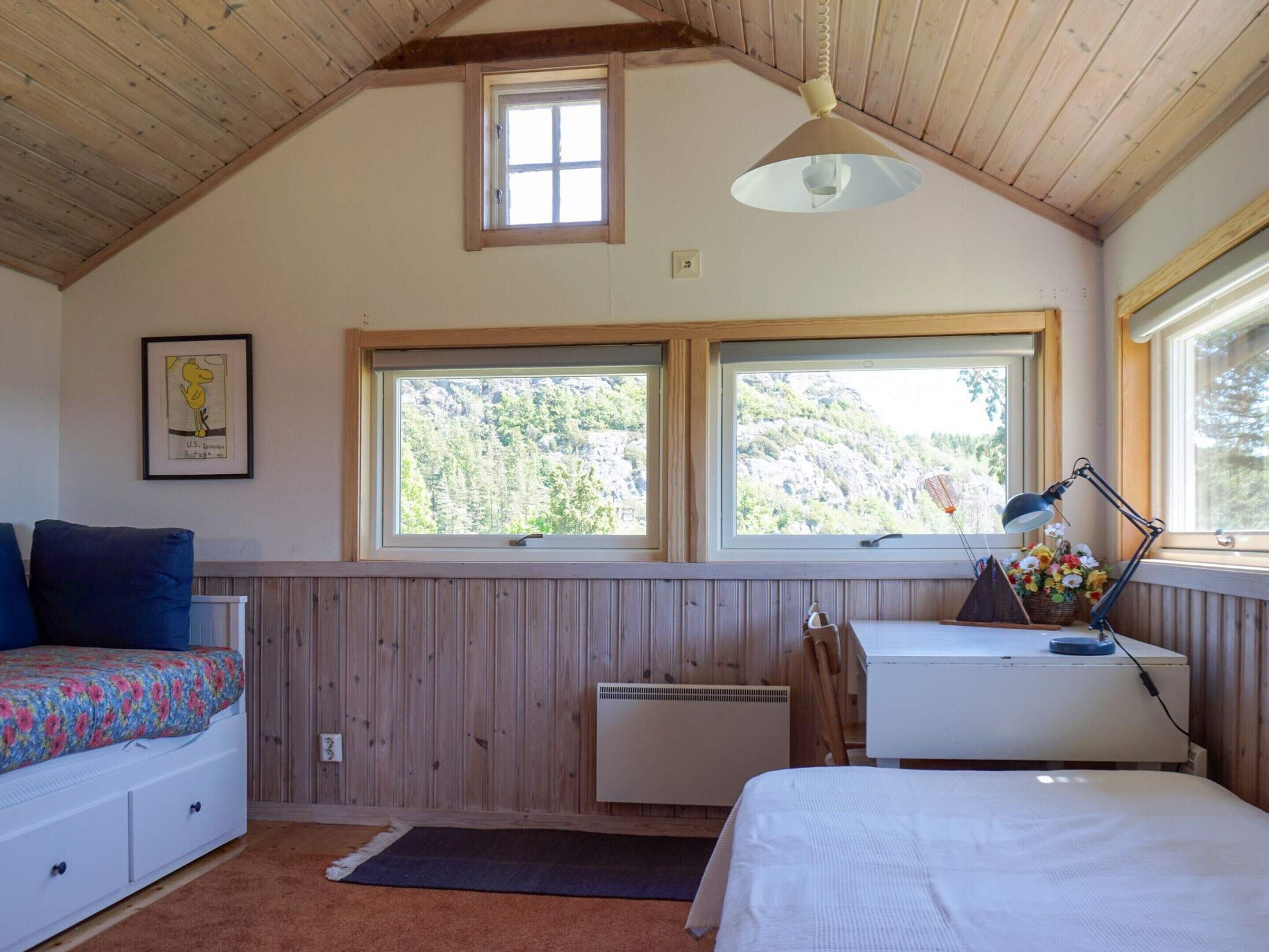 A bedroom with two windows, a bed, a desk, a chair, and a radiator.