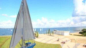 A sailboat on a calm body of water with a clear sky and distant land. - Liebevoll Eingerichtetes Apartement (Rechlin)