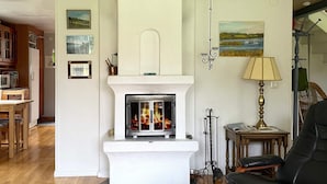 A living room with a fireplace, a dining area, and a seating area with a leather chair and ottoman. - 4 Star Holiday Home in Torso (Torsö)