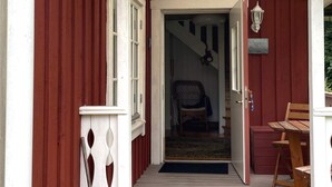 A wooden exterior with a red door, a white porch railing, and a wooden bench. - 4 Star Holiday Home in Torso (Torsö)