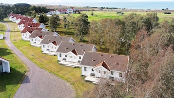 Una hilera de casas blancas con tejados rojos, un camino de grava y vistas al mar.