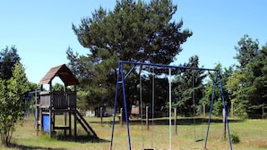 A playground with a swing set and a wooden playhouse. - Ferienhaus am Vilzsee, Mirow (Mirow)