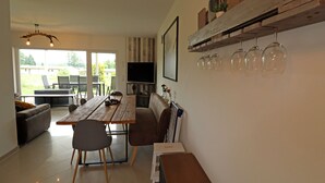 A dining area with a wooden table, chairs, and a television. There is a sofa and a bookshelf with decorative items. - Ferienhaus Seeluft in Klein Labenz (Warin)