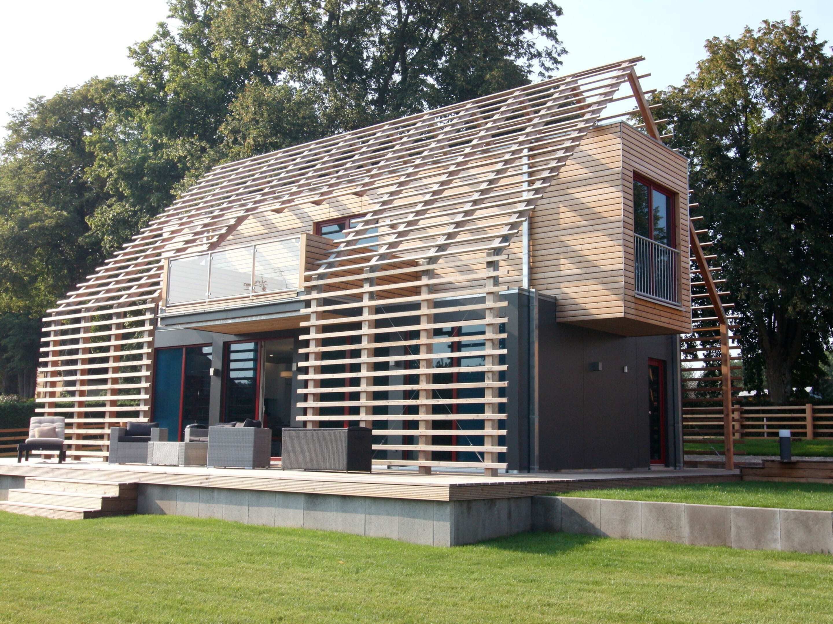 Une maison moderne avec un toit en pente, de grandes fenêtres et un balcon.