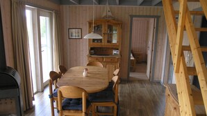 Ein Esszimmer mit Holzboden, einem großen Tisch mit Stühlen, einer Pendelleuchte und einem Holzschrank.