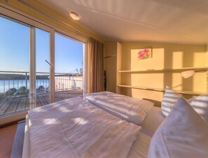A hotel room with two beds, a large window with a view of a body of water, and a painting on the wall. - Elegant Eingerichtete Ferienwohnung (Mirow)