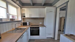 Eine kompakte Küche mit weißen Schränken, einer Mikrowelle, einem Spülbecken und einem Backofen.