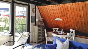A cozy room with a blue sofa, wooden ceiling, and a table with chairs. - Holiday Home in Burhave Near the sea (Butjadingen)