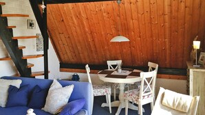 A cozy room with a blue sofa, a round table with chairs, and a wooden ceiling. - Holiday Home in Burhave Near the sea (Butjadingen)