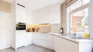 Een moderne keuken met witte kasten, een ingebouwde oven, een koffiezetapparaat en een raam met uitzicht.