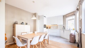 Een moderne keuken met witte kastjes, een houten eettafel en een hangende lamp.