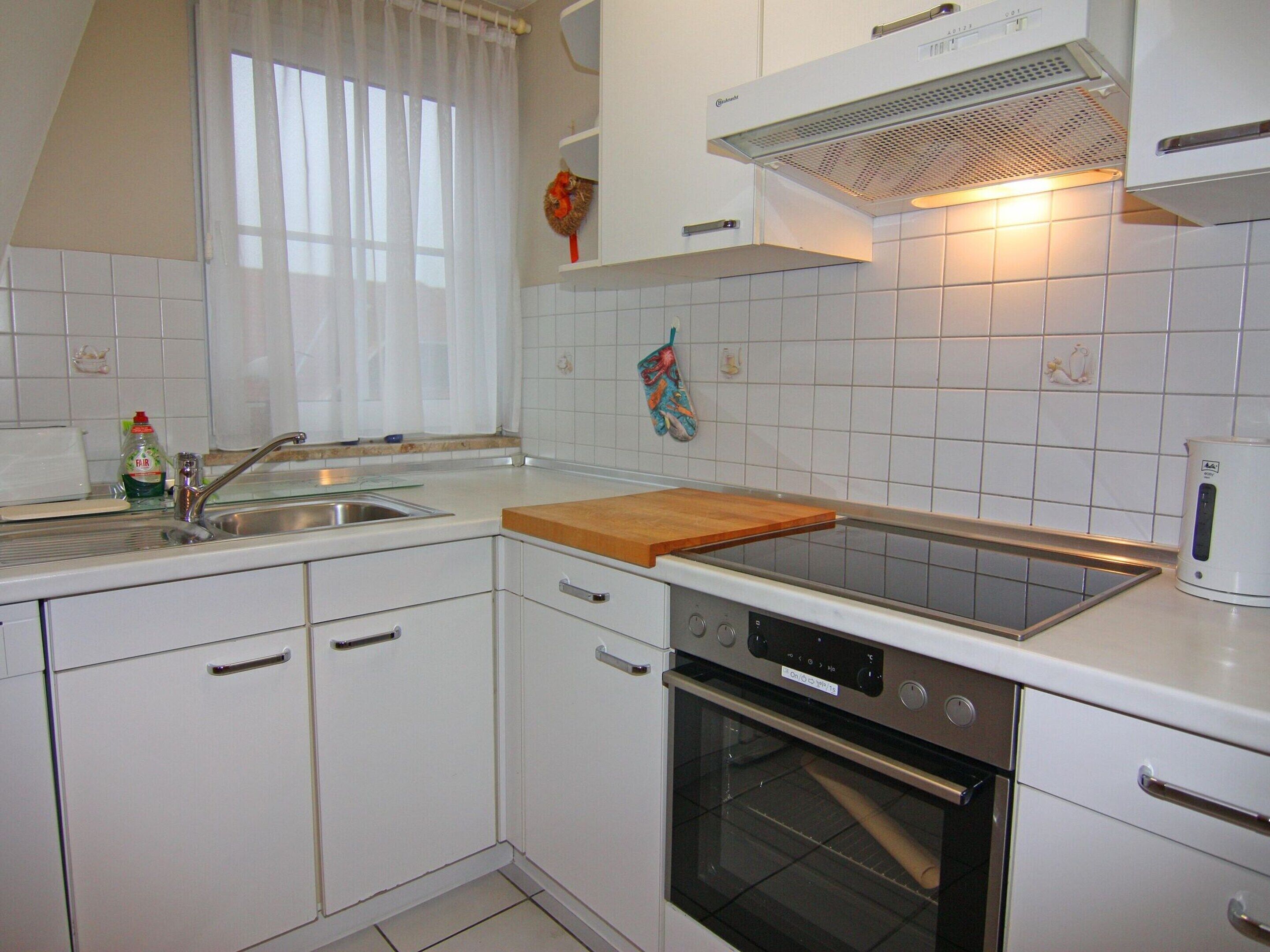 A kitchen with white cabinets, a stainless steel sink, a built-in oven, and a wooden countertop.