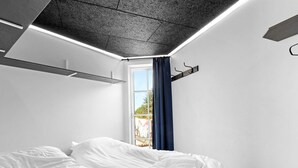 A modern bedroom with a bed, a window with curtains, and a ceiling with recessed lighting. - Cozy Retreat in Nordjylland - By Traum Ferienwohnungen (Blokhus)