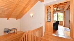 A wooden interior with a staircase, a table with chairs, and a view through a doorway to another room. - Ferienhaus aus Holz in der Nahe des Skigebiets (Bayerisch Eisenstein)